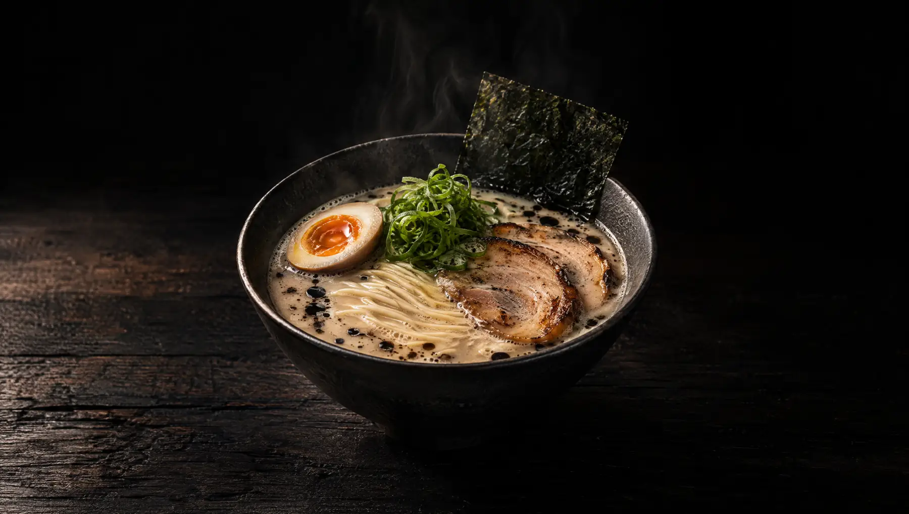 Kuroyu tonkotsu: milky pork broth, chashu, soft egg, negi and nori in a black bowl.